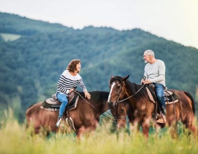 a-senior-couple-riding-horses-in-nature-TKS4UMD